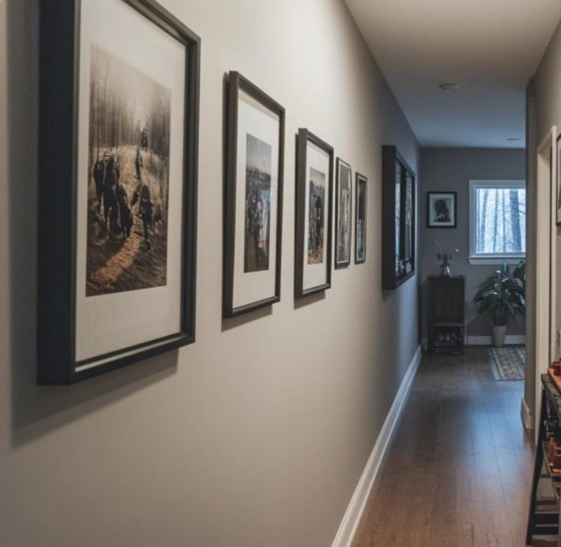Framed photographs hung in a straight line along a narrow hallway wall, demonstrating how to display wall art in tight, linear spaces for visual impact.