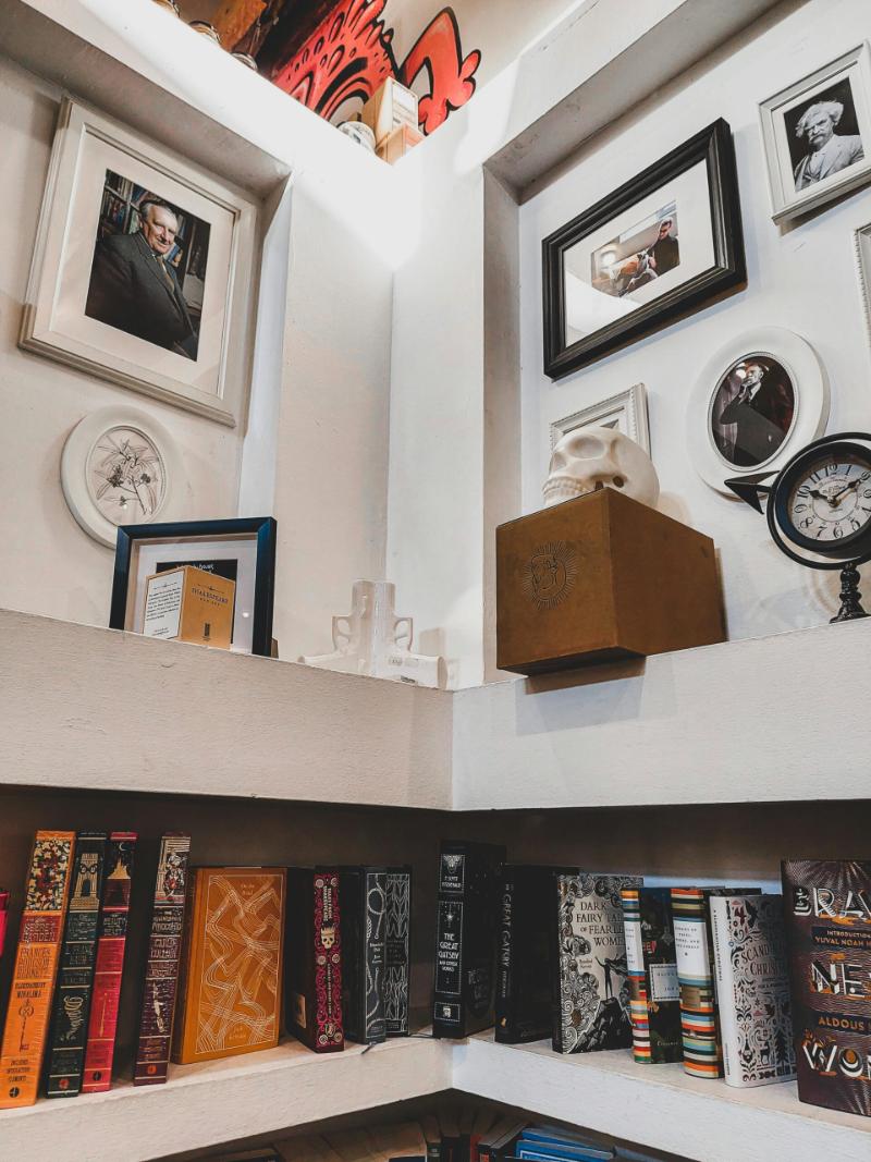 Framed portraits and wall art arranged in a corner gallery display above built-in bookshelves, showing how to decorate challenging corner spaces with art.